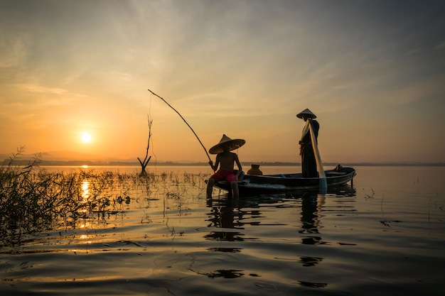Рыбаки Рыболовные удочки с крючком выходят на рыбалку рано утром на деревянной лодке