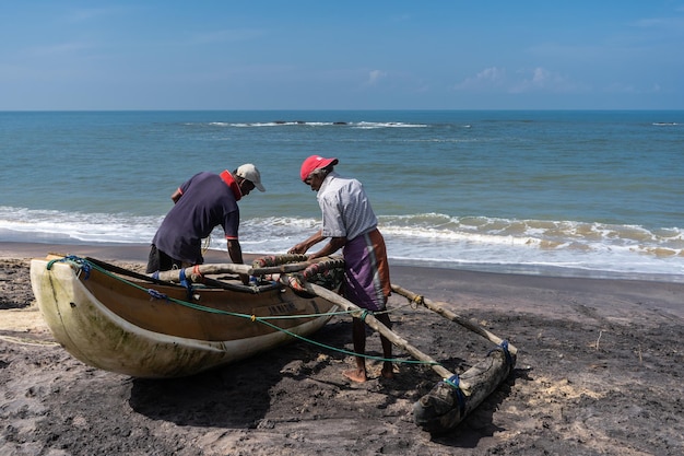 Foto i pescatori prendono il pescato dalla loro barca sulla spiaggia