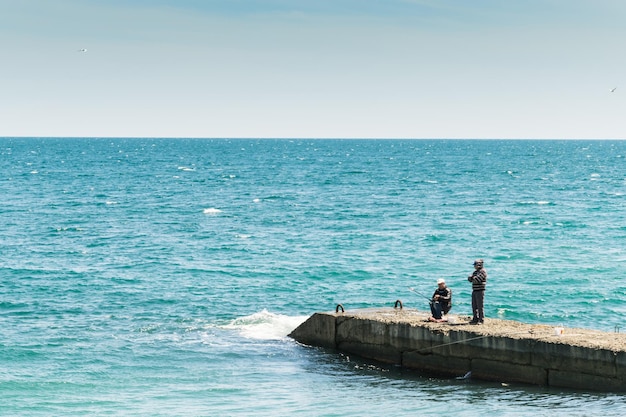 Рыбаки на пирсе ловят рыбу в море