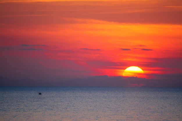 夕暮れ時に輝く太陽の下で一人で漁船