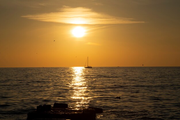 地平線上の漁船、海に沈む夕日。穏やかな海、珊瑚の空、夜釣り