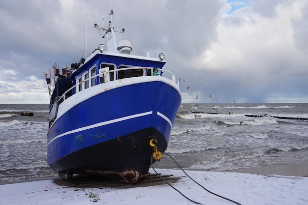 Fishing boat on shore with snow in winter