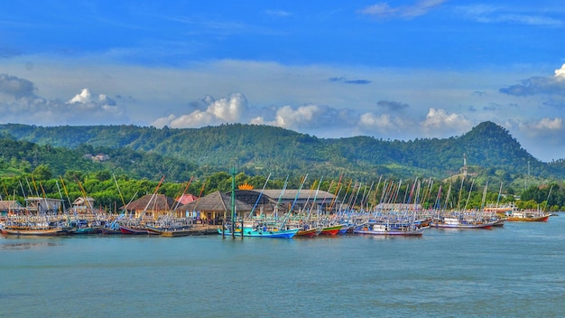 Fishing boats are moored in the harbour behind it is a beautiful cluster of mountains