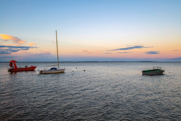 Fishing boats docked at the pier by the shore at sunset.