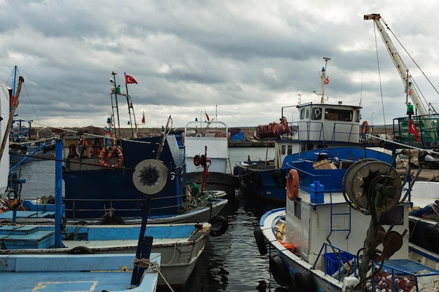 fishing boats moored on river against cloudy sky