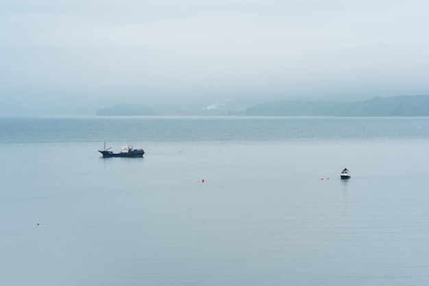 Fishing boats at sea against the background of a distant foggy coast