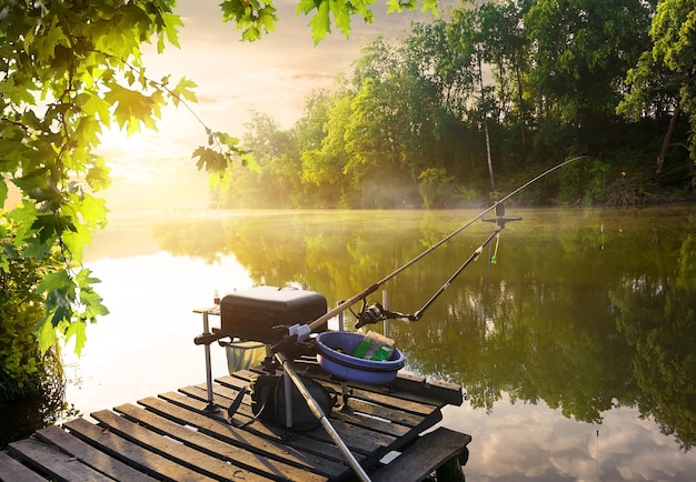 Fishing equipment on wooden pier and calm river in the morning