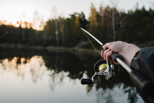 Fisherman with rod, spinning reel on the river bank. Fishing for