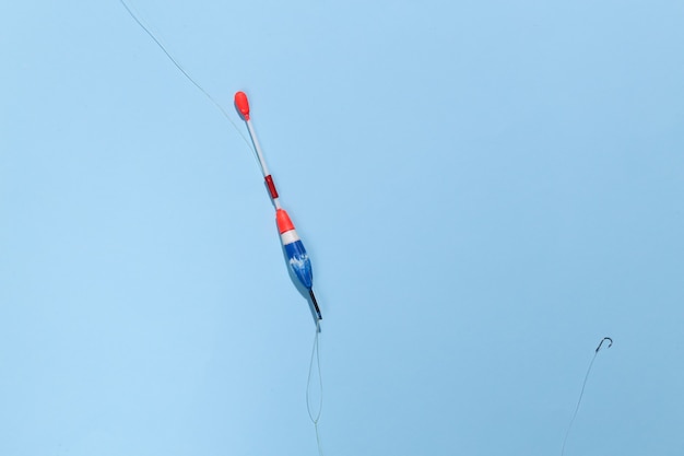 Fishing float with a hook on a bright blue background