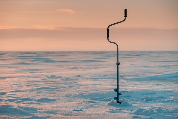 Fishing ice drill. Frozen sea in the background