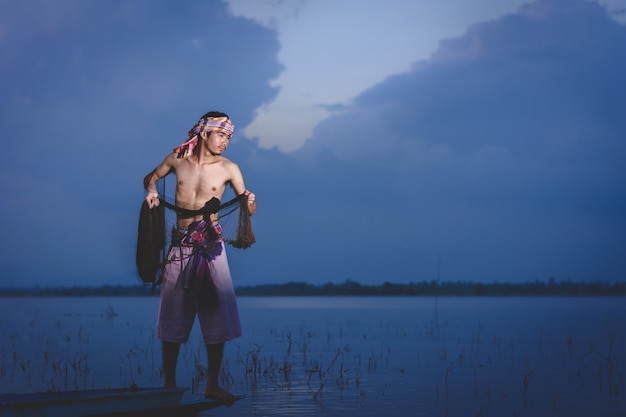 fishing man use throwing net to catch fish in lake at sunset