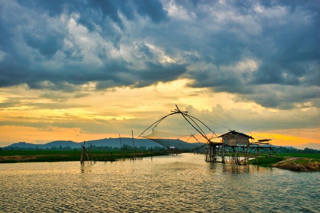 A fishing net is in the water with a cloudy sky in the background.