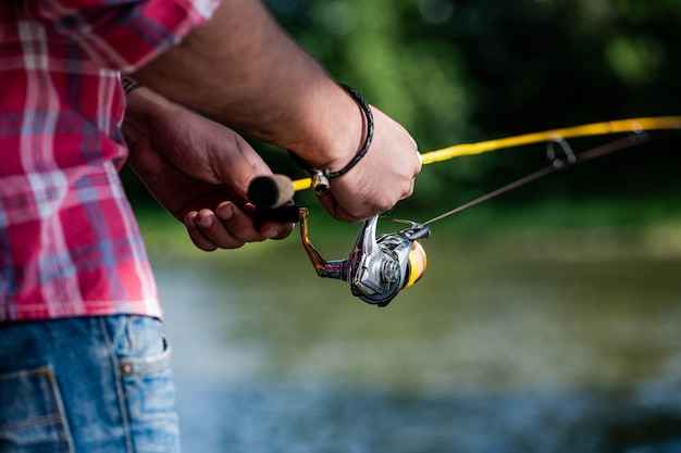 Fishing Reel Fishing Rod with Aluminum Body Spool Fishing Gear Fish Supplies and Equipment Fishings reel closeup on the background of the river