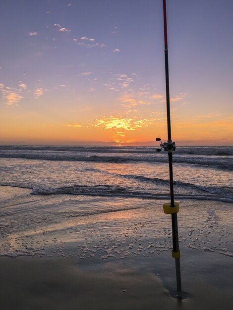 Fishing rod on beach at sunset surfing cast