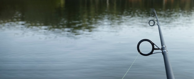 Fishing rod over freshwater with copy space banner