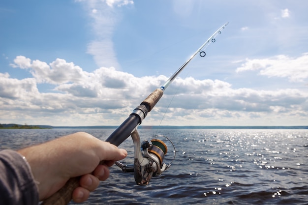 Fishing rod in the hand on the river on a sunny day.