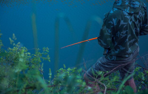 Photo fishing rod in the hands of a fisherman on the lake fisherman's hands with spinning on the background of water