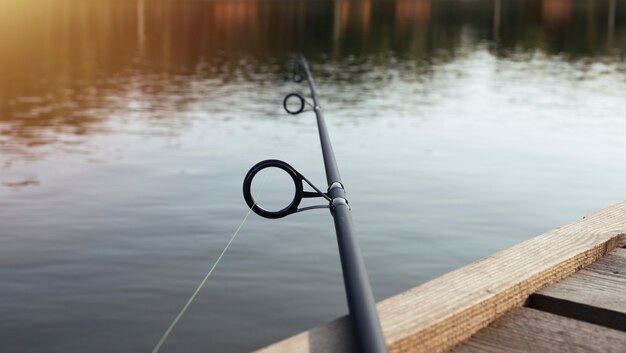 Fishing rod over lake water lying on wood jetty
