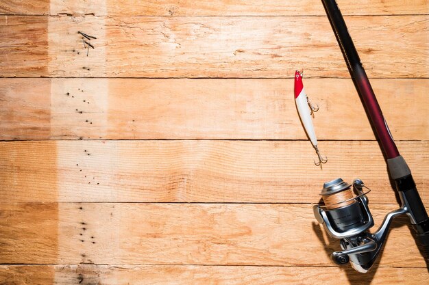 Photo fishing rod with red white fishing bait wooden plank