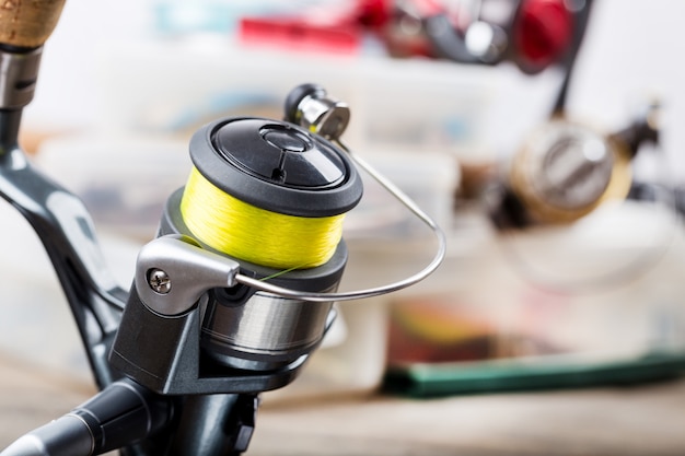 Fishing rod with reel on table of tackles in boxes