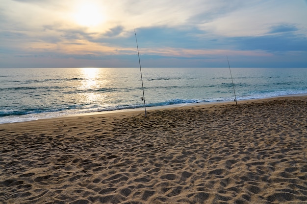 Fishing on the sandy beach of the sea on a sunset.