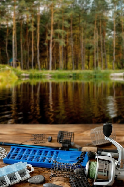 Рыболовные снасти и аксессуары на столе на фоне лесного озера Selective Focus