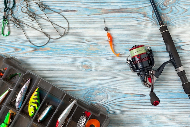 Fishing tackle - fishing spinning, hooks and lures on blue wooden background