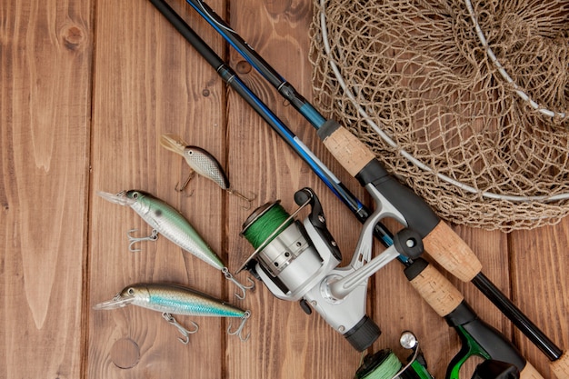 Fishing tackle - fishing spinning, hooks and lures on wooden background with copy space