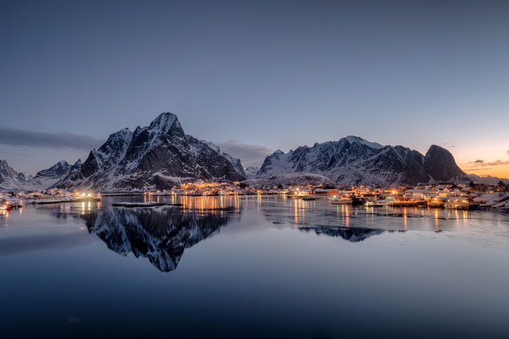फोटो fishing village illumination with mountain range  reflection on coastline at dawn