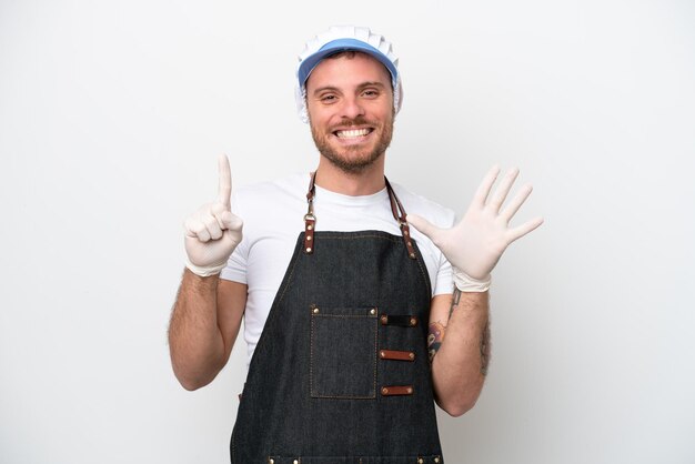 Fishmonger man wearing an apron isolated on white background counting six with fingers