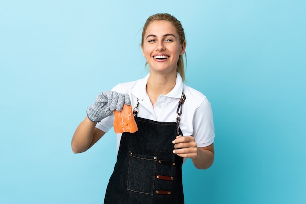 Fishmonger wearing an apron and holding a raw fish blue laughing