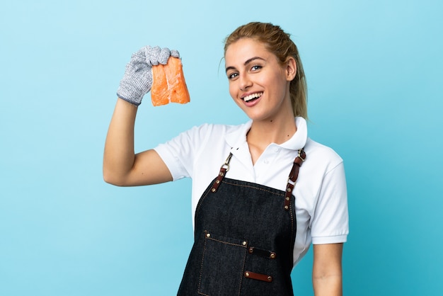 Fishmonger wearing an apron and holding a raw fish over isolated blue space