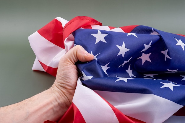 Fist gripping a United States flag tightly on a green background Concept of the strength of the peo