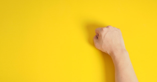 Fist hand on yellow background.Man right hand.