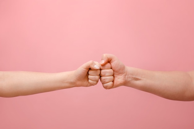 Fist hands of man and woman on pink background