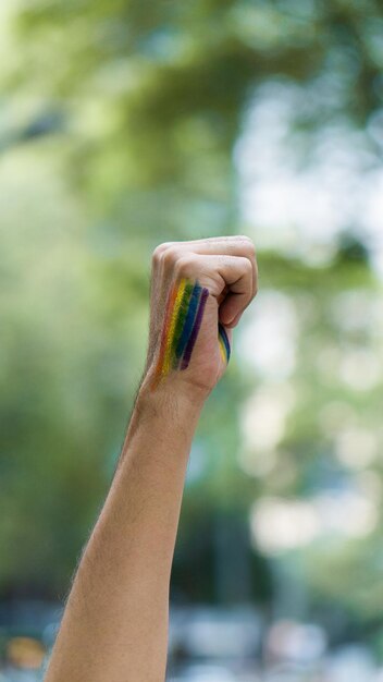 Fist raised in rainbow makeup as a symbol of gay pride.