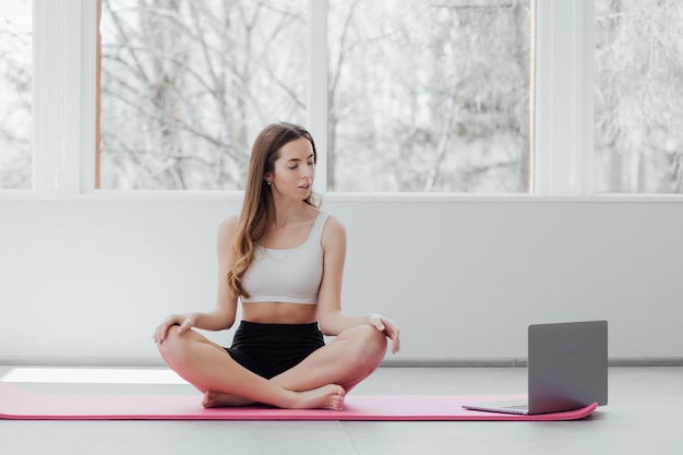 Fit adult woman resting in gym after a hard workout. long
haired caucasian coach sitting on yoga mat