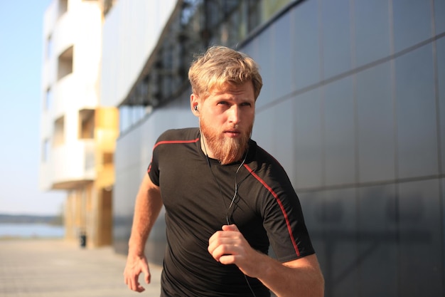 Fit athlete. Handsome adult man running outdoors to stay healthy, at sunset or sunrise. Runner