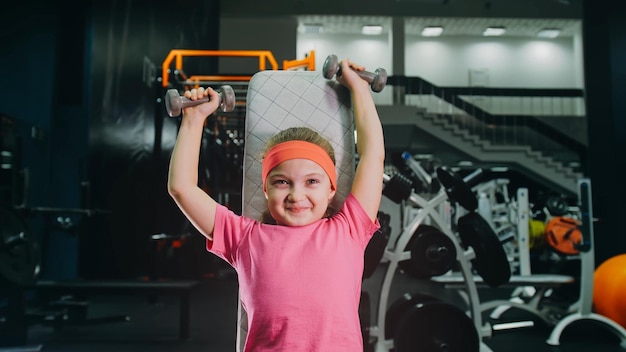 Fit athletic baby girl work out with dumbbell doing her fitness exercise children activity training