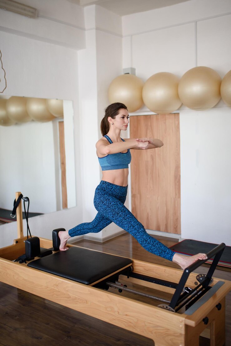 A fit athletic woman does an exercise on a reformer in the gymPilates