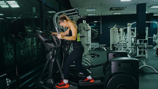 Fit atletische vrouw oefenen op een elliptische machine Gespierde vrouwen activiteit opleiding in moderne sportschool training in een elliptische Walking Trainer