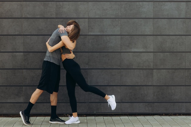 Fit beautiful woman and handsome muscular man after outdoor training hugging and smiling Couple Healthy sporty lifestyle concept Real people emotions