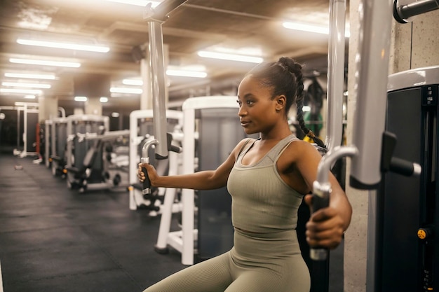 Photo a fit black sportswoman is practicing chest on exercise machine in a gym