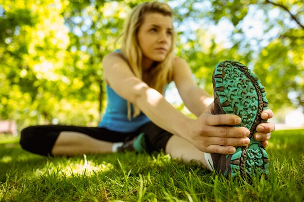 Fit blonde die zich uitstrekt over het gras