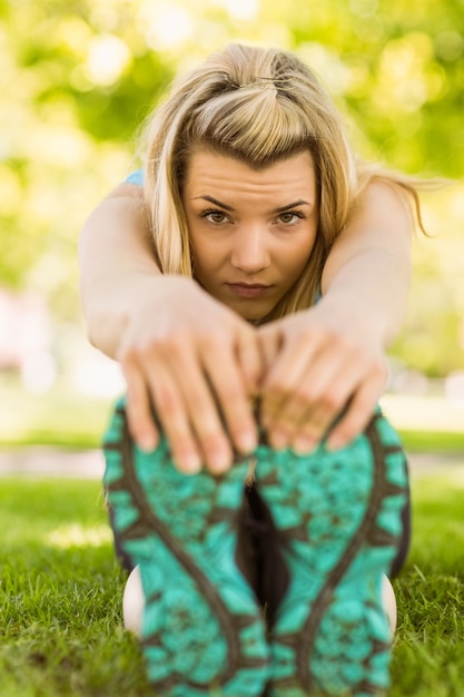 Foto fit blonde die zich uitstrekt over het gras