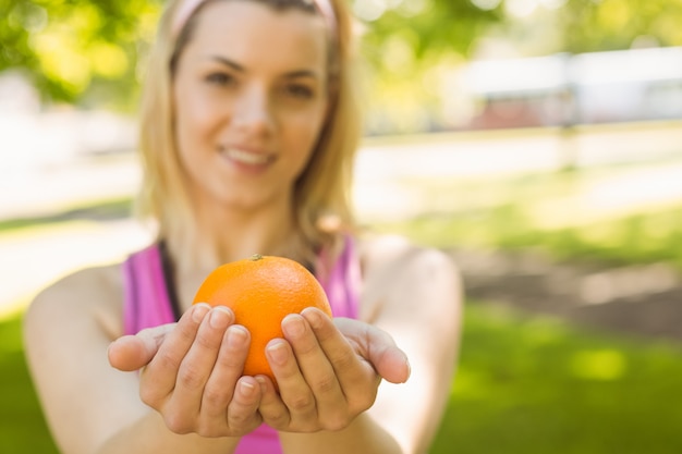 Fit blonde holding an orange on a sunny day