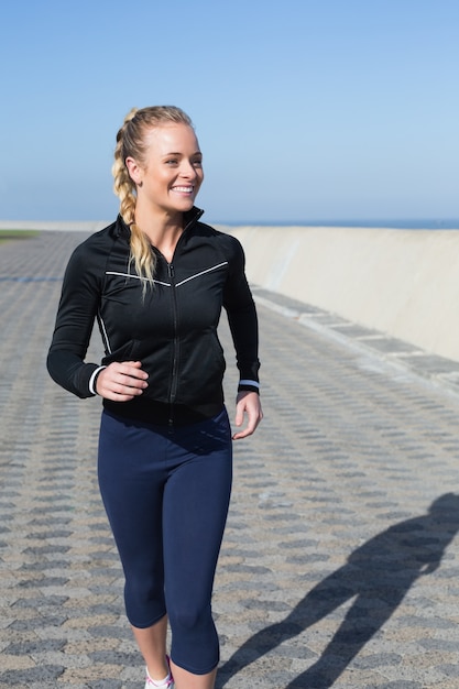 Fit blonde joggen op de pier