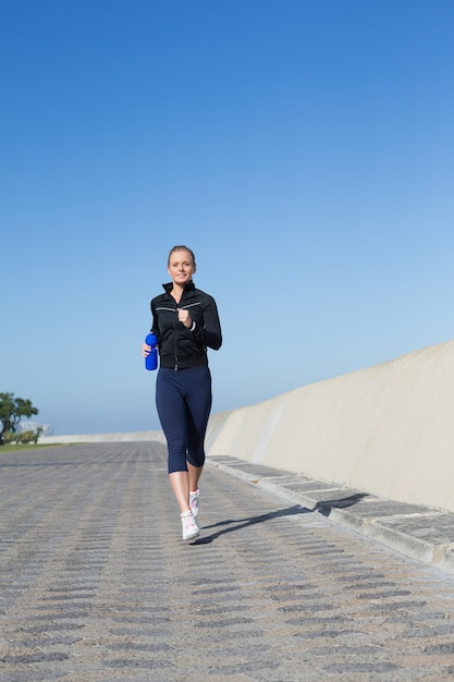 Fit blonde jogging on the pier