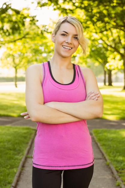 Fit blonde smiling at camera in the park