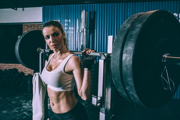 Fit blonde vrouw opleiding tillen een staaf gewichten in sportschool